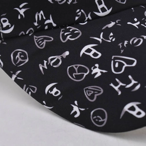 Detail of black baseball cap featuring silver graffiti prints and heart patterns