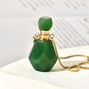 Macro shot of green aventurine flame-shaped perfume bottle pendant on a gold box chain