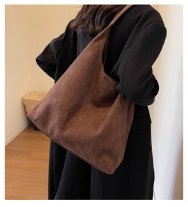 Detailed side view of the large capacity dark brown suede tote bag on a female model