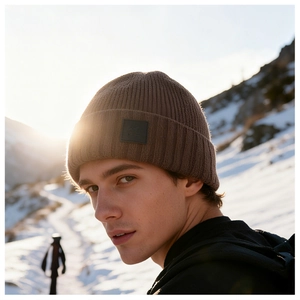 Detail of core-spun yarn knit beanie with leather logo patch against a snowy mountain sunset