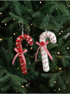 Detail of red glitter and striped candy cane ornaments with bows on a Christmas tree