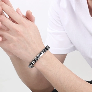 Detail of men's punk style square clasp and vintage weave chain bracelet in silver black