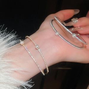 Detail shot of double-layer open bracelets with zircon and pearls on a model wrist