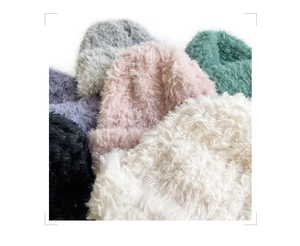 Close-up of soft plush knit beanies in various colors showing fuzzy texture and warmth