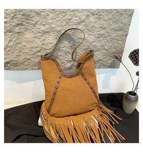 Detail of brown suede tote bag featuring sun embossing, metal studs and bohemian fringe
