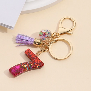 Detail view of resin letter V keychain with red glitter and purple tassel accessory