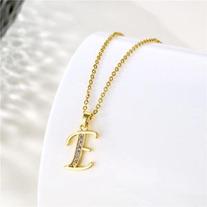 Macro shot of gold letter E pendant with zircon stones on a stainless steel chain