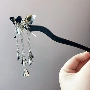 Detail eines flüssigen Schmetterlings-Haarstabs mit langen Metallquasten und Glöckchen