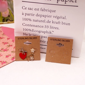 Asymmetric 925 sterling silver heart earrings displayed on professional card packaging