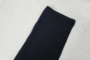 Close-up of double-stitch sewing detail and fabric texture on a black bodycon jumpsuit