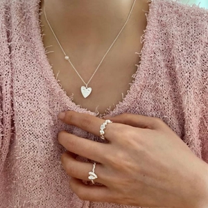 Close-up of S925 sterling silver heart ring set and matching necklace on model