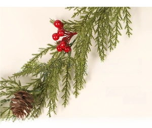 Detail of artificial Christmas garland with green cypress needles and red berries