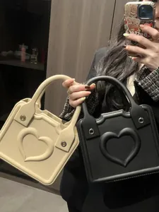 Detail view of heart embossed square tote bags in black and cream with silver metal buckles