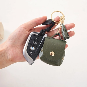 Dark green PU leather case for AirPods with gold keychain and tassel, handheld view