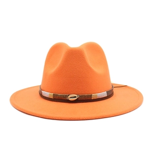Detail of orange wool fedora hat with bohemian woven band and golden shell buckle decoration