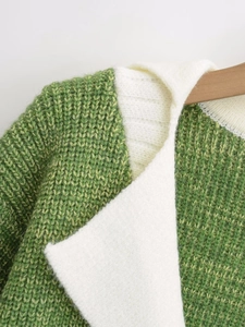 Detail of color block V-neck cardigan with grass green knit texture on a wooden hanger