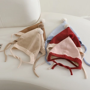 Detailed view of knitted baby elf hats with soft pom poms and secure chin straps