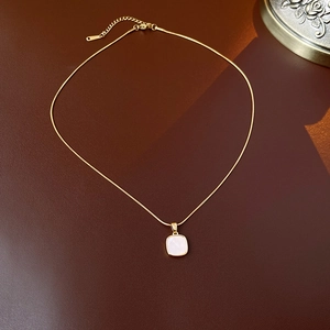 Détail d'un collier en titane doré avec pendentif carré en nacre blanche élégante