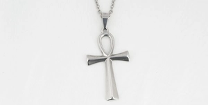 Detailed view of silver Ankh cross pendant necklace with metallic chain on white surface