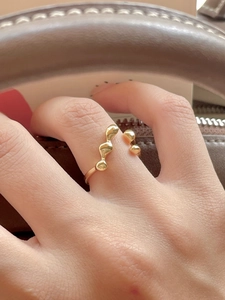 Elegant gold irregular textured open ring worn by a model on a brown leather bag