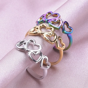 Adjustable hollow heart rings in gold, silver, and iridescent finishes on pink silk