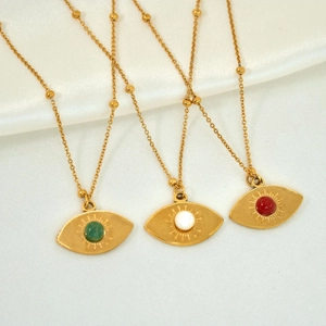 Detail view of evil eye necklaces with colorful natural stones on silk background