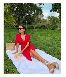 Detail of red V-neck side slit dress on a model during an outdoor picnic