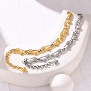Close-up of stainless steel paperclip chain bracelets with heart charms in gold and silver