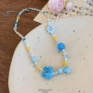 Détails d'un collier de perles colorées avec pendentif crabe bleu, étoile et fleurs