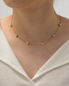 Close-up of gold titanium necklace with round zircon inlays worn on a model's neck