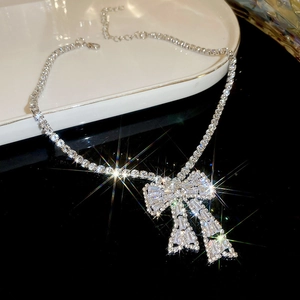 Detailed macro view of a sparkling silver bow pendant encrusted with clear rhinestones.