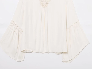 Detail of elegant bell sleeves and lace trim on this cream pleated bohemian blouse
