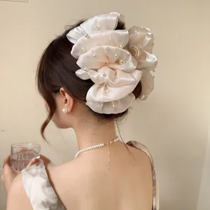 Vista dettagliata della pinza per capelli a fiore in seta crema con perle su acconciatura