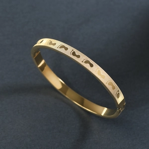 Detail shot of the gold stainless steel bangle with engraved footprint patterns