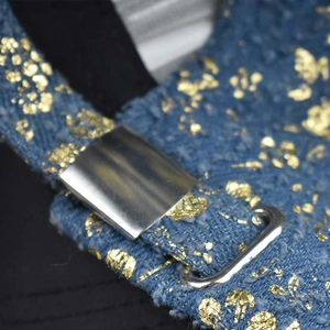 Detailed close-up of blue denim baseball cap with gold foil accents and silver metal buckle