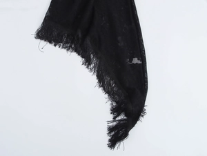 Detailed macro shot of black translucent lace fabric with elegant fringed edges on shawl