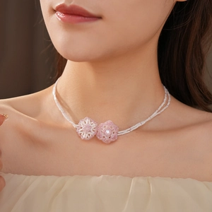 Close-up of double-layer beaded necklace featuring pink and white floral pendants on neck