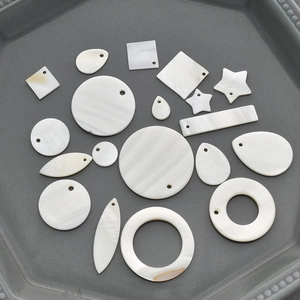 Various geometric white mother of pearl shell pendants in a decorative tray