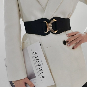 Close-up of black elastic wide belt with a geometric gold metal buckle on model