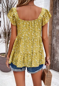 Back view of a floral square neck blouse paired with denim shorts in a resort setting