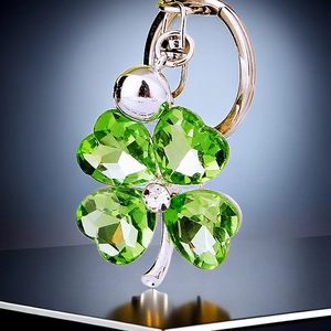 Detail of silver clover keychain with green crystal leaves and small bell attachment