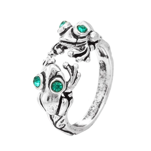 Detailed close-up of retro silver frog rings with sparkling green rhinestone eyes