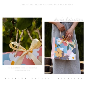 Detail of floral gift bag with yellow satin bow and woven handles in outdoor setting