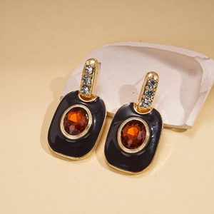 Vue macro de boucles d'oreilles dorées vintage avec émail noir et ambre incrusté