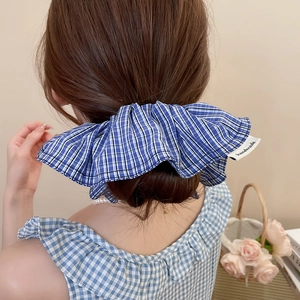 Détail d'un chouchou à carreaux bleus avec étiquette handmade sur un mannequin