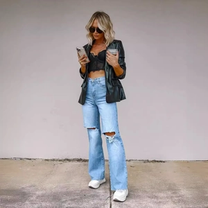 Jean bleu clair troué à jambes larges pour femme avec blazer noir et top dentelle