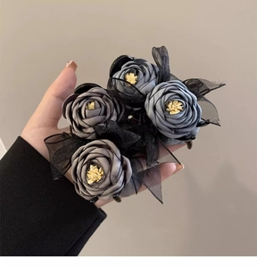 Detail of grey fabric roses and black lace mesh bow hair clip for elegant buns