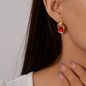 Close-up of red water drop earrings with gold metal trim worn by a model