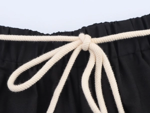 Dettaglio vita dei pantaloni neri ricamati con cintura in corda di cotone intrecciata