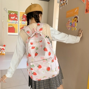 Detail view of a pink strawberry print backpack shown on back of a student model